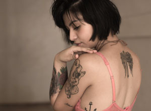 A female with delicate with delicate tattoos on her arm and back