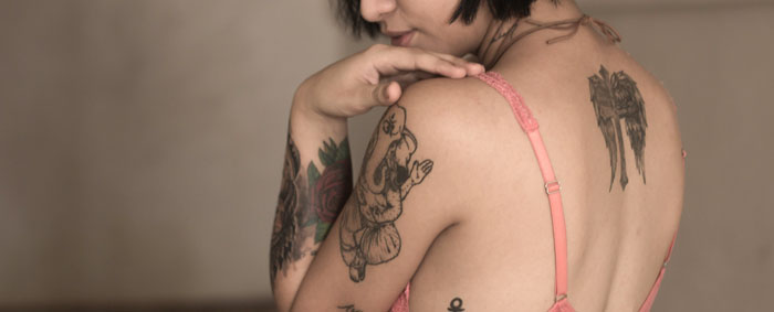 A female with delicate with delicate tattoos on her arm and back