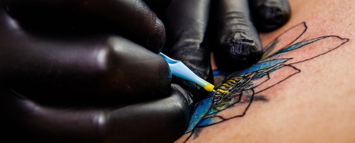 A tattoo artist tattooing on scarred skin.