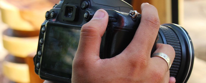 Tattooed hands holding a camera.